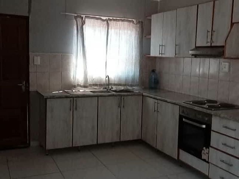 A functional kitchen featuring built-in cabinetry, tiled backsplash, integrated oven and cooktop, and tiled flooring, offering a practical layout for daily use.