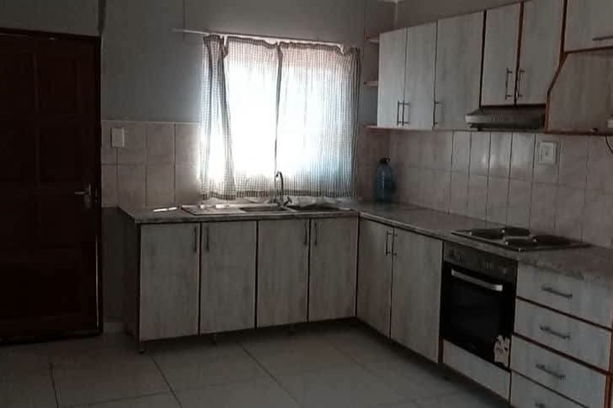 A functional kitchen featuring built-in cabinetry, tiled backsplash, integrated oven and cooktop, and tiled flooring, offering a practical layout for daily use.