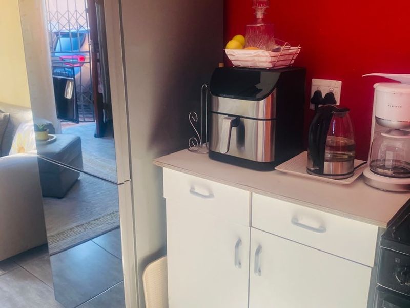 A compact kitchen area featuring white cabinetry, tiled flooring, and a built-in oven, with a view into the adjacent living space.