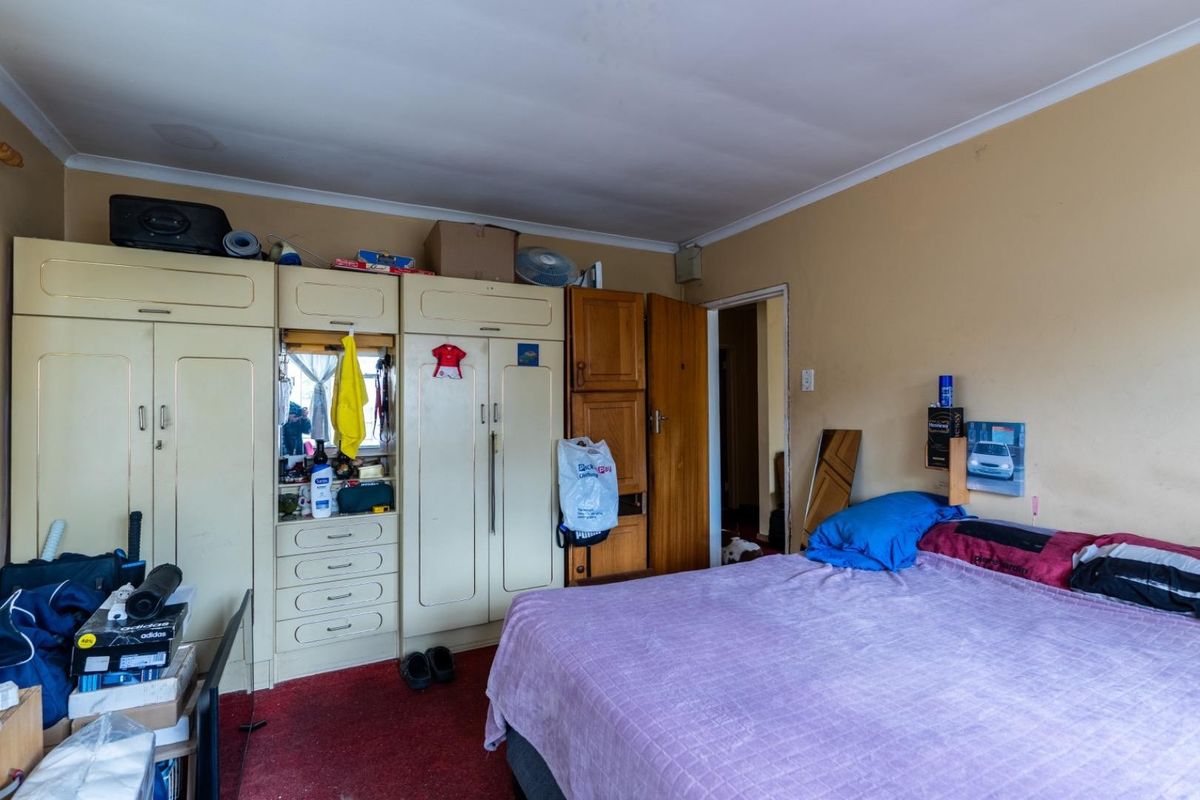 A bedroom featuring built-in wardrobe cabinetry and carpeted flooring, offering a functional space with potential for cosmetic updates.