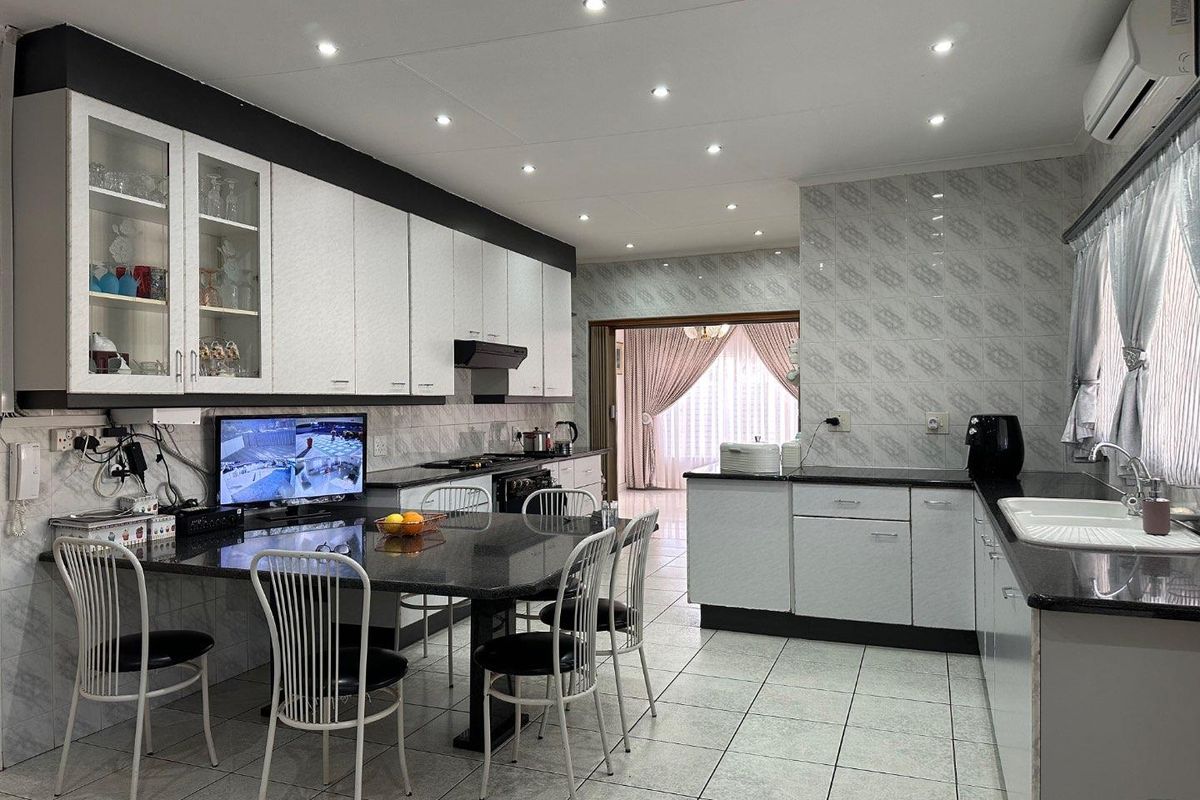 Spacious kitchen featuring granite countertops, built-in cabinetry, integrated stove and extractor fan, recessed ceiling lighting, and tiled flooring throughout.
