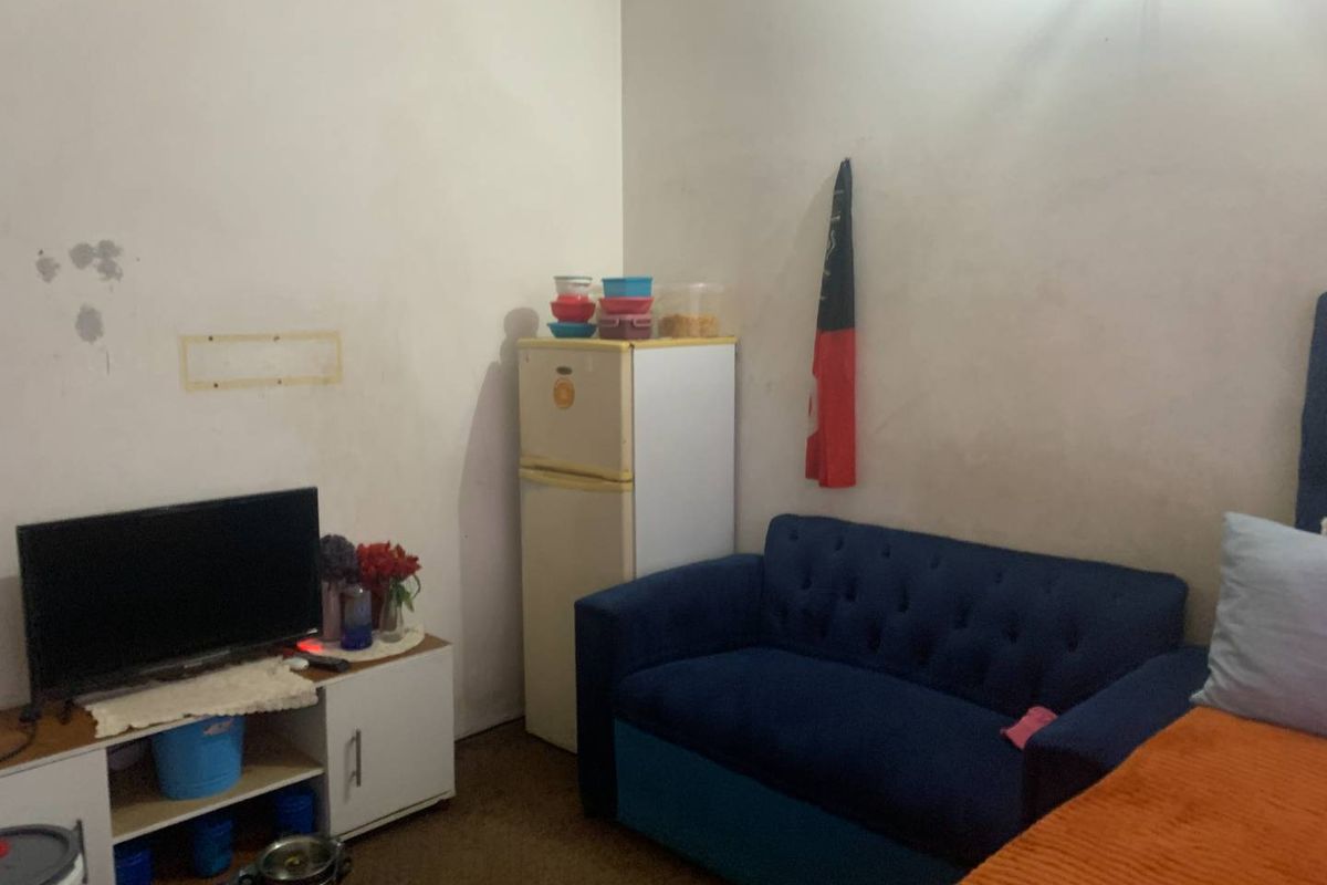 A compact living area featuring plain walls and basic flooring, suitable for a small studio or bedroom setup.