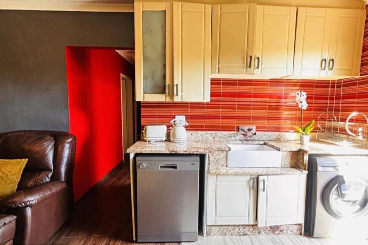 Compact kitchen area featuring granite countertops, a farmhouse-style sink, built-in cabinetry, and integrated space for a dishwasher and washing machine.