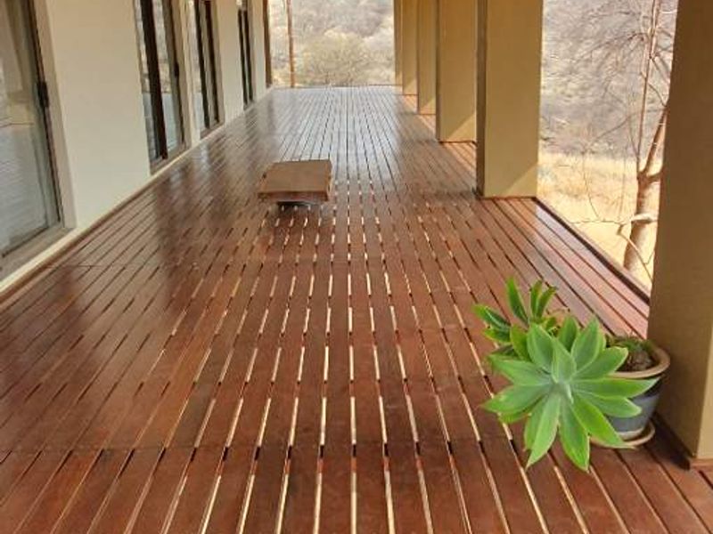 A spacious covered patio featuring timber decking, a corrugated metal roof, and expansive views, providing an ideal outdoor entertainment area.