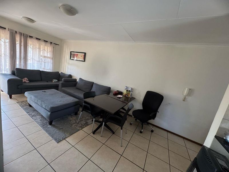 A spacious living area featuring neutral tiled flooring and an intercom system, offering a functional layout for comfortable daily living.