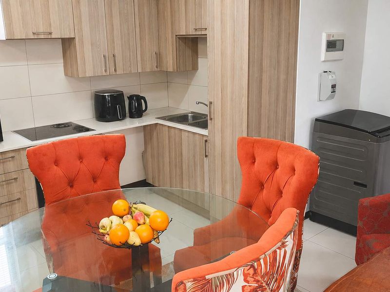 Modern open-plan kitchen featuring light wood-grain cabinetry, integrated electric hob, and tiled finishes, seamlessly flowing into the dining area.