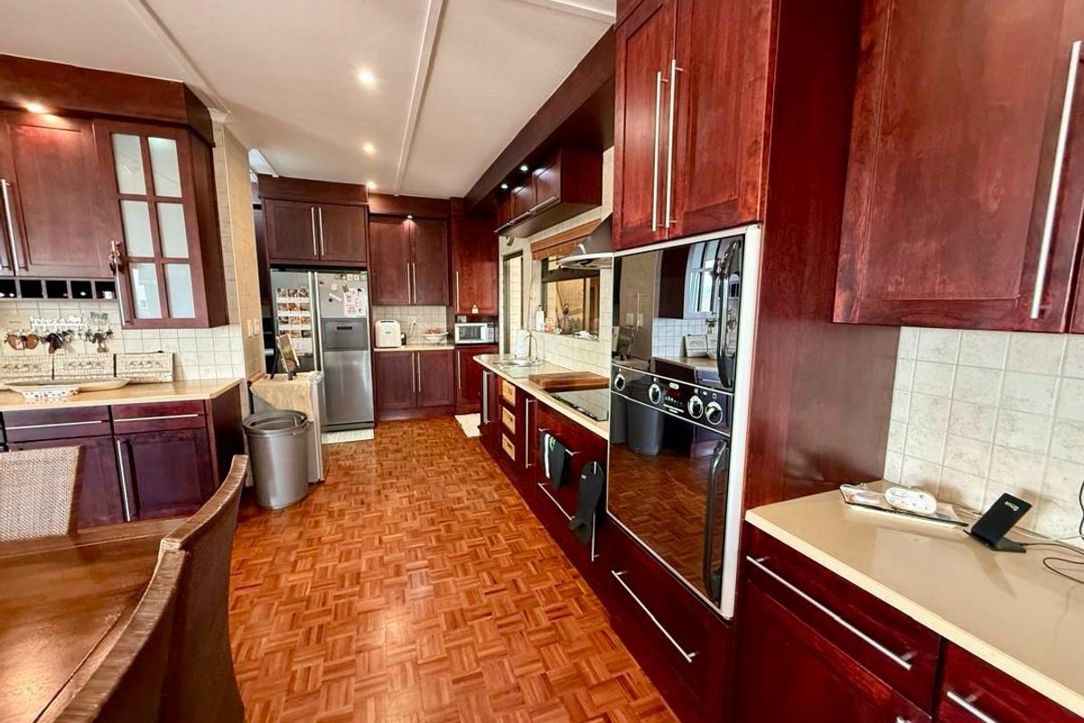 Spacious kitchen featuring dark wood cabinetry, integrated oven, tiled backsplash, and traditional parquet flooring, offering a functional layout with ample storage space.