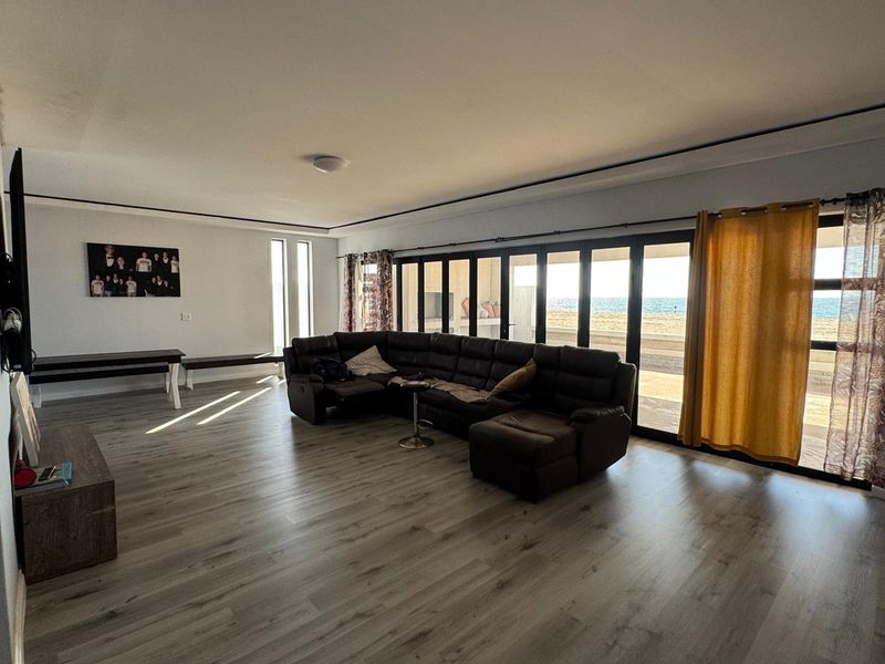 Spacious living room featuring modern laminate flooring and expansive sliding glass doors that provide seamless access to the outdoor area and ocean views.