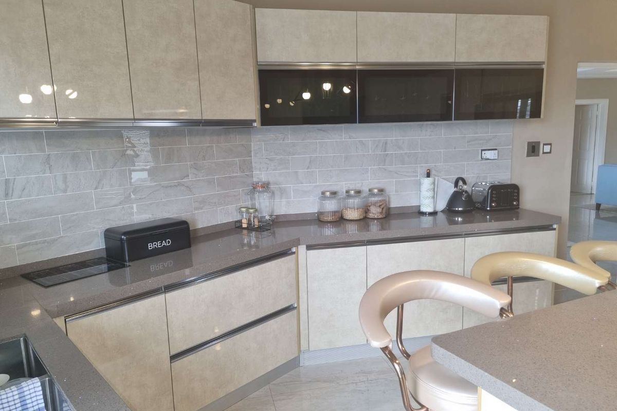 Modern kitchen featuring sleek cabinetry, stone countertops, and a stylish tiled backsplash, offering a clean and functional culinary space.
