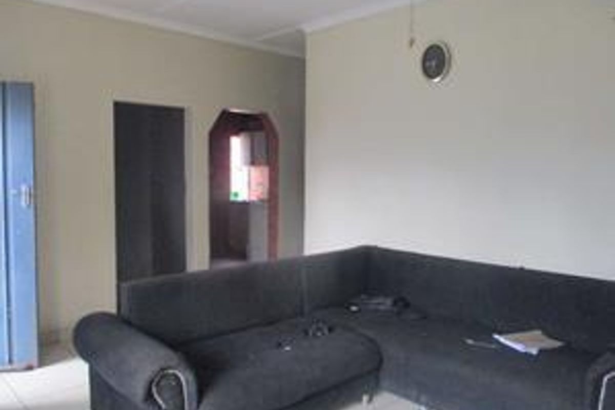A living room area featuring tiled flooring and neutral wall finishes, providing a functional space with access to adjacent rooms.