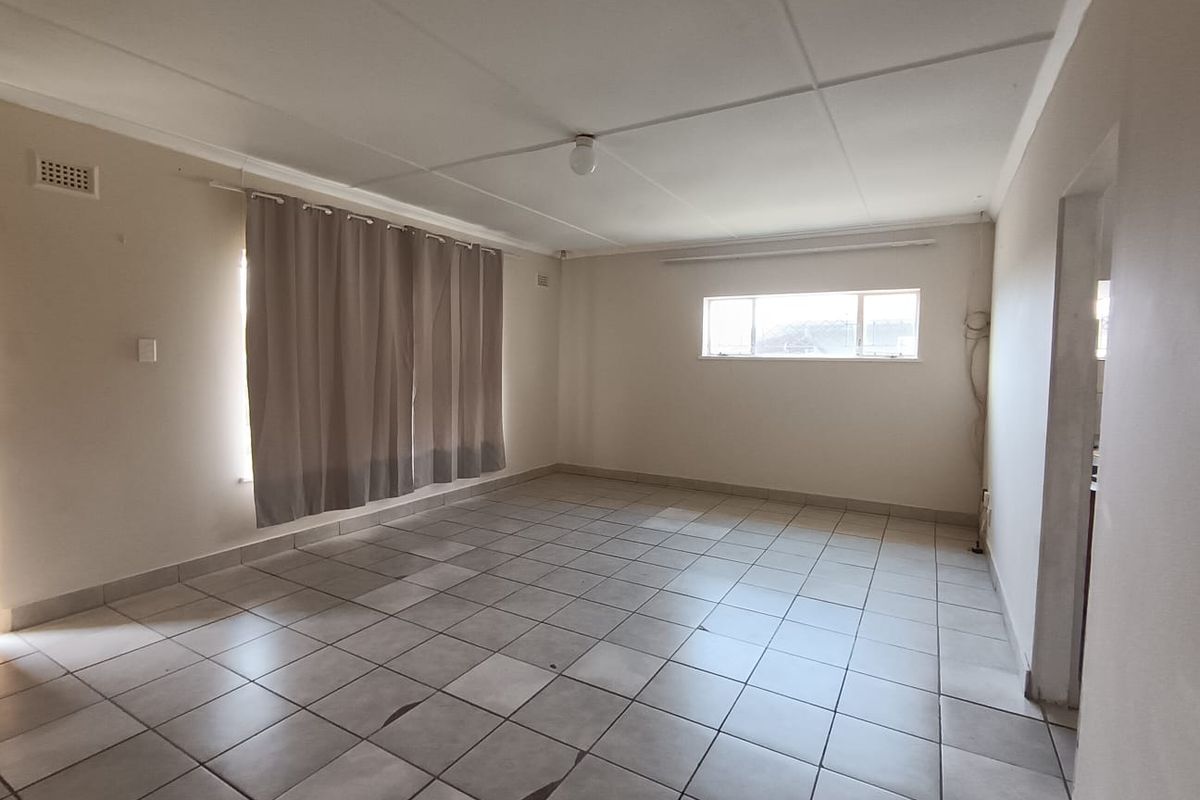 An empty living room featuring tiled flooring, neutral walls, and natural light from windows, providing a blank canvas for interior design.