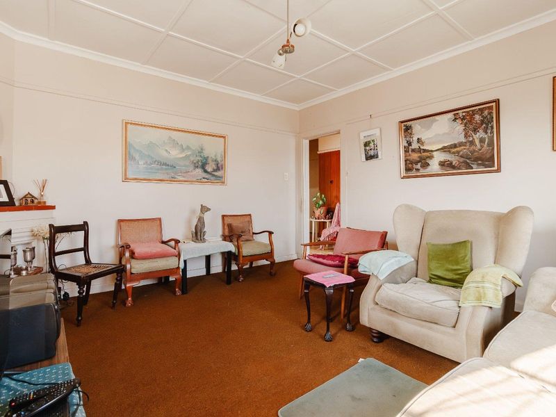 A traditional living room featuring a fireplace, picture rails, and a tiled ceiling, currently finished with dated carpeting.