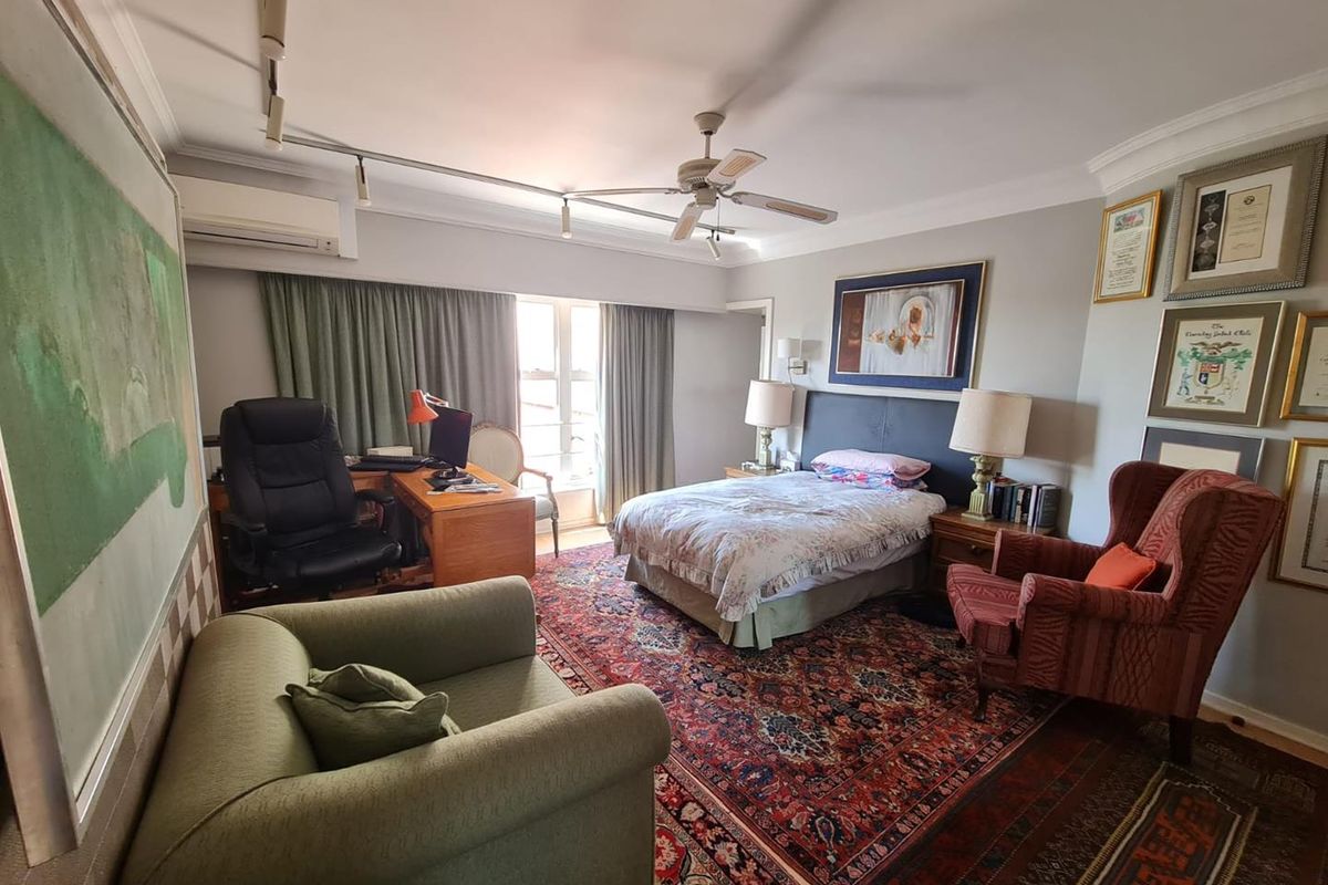 Spacious bedroom featuring a ceiling fan, wall-mounted air conditioning unit, and track lighting, offering a comfortable and functional living space.