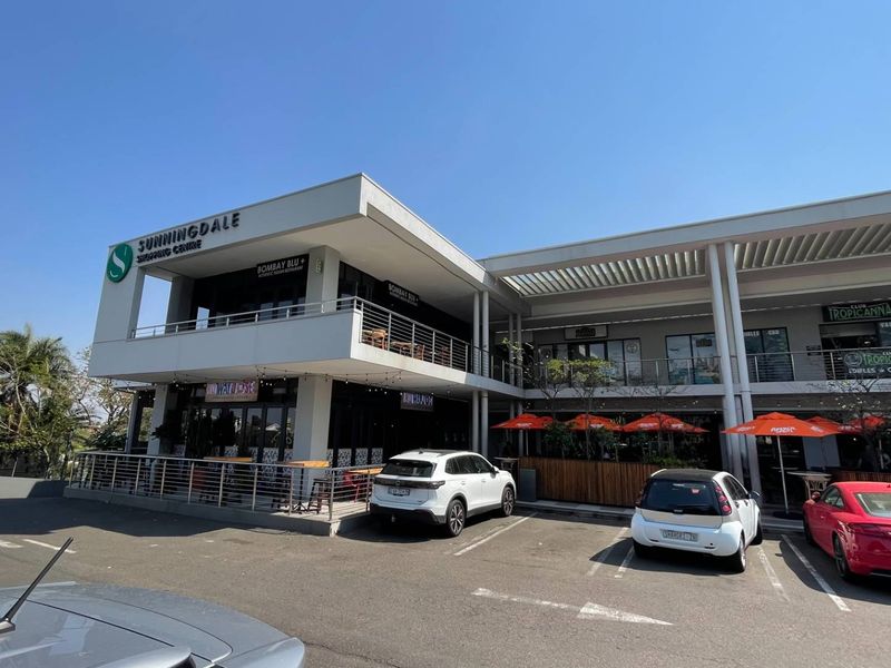 Exterior view of the Sunningdale Shopping Centre featuring a modern multi-level facade, balcony areas, and ground-level parking facilities.