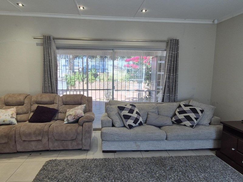 A comfortable living room featuring tiled flooring, recessed downlighting, and a large sliding glass door providing access to the outdoor area.