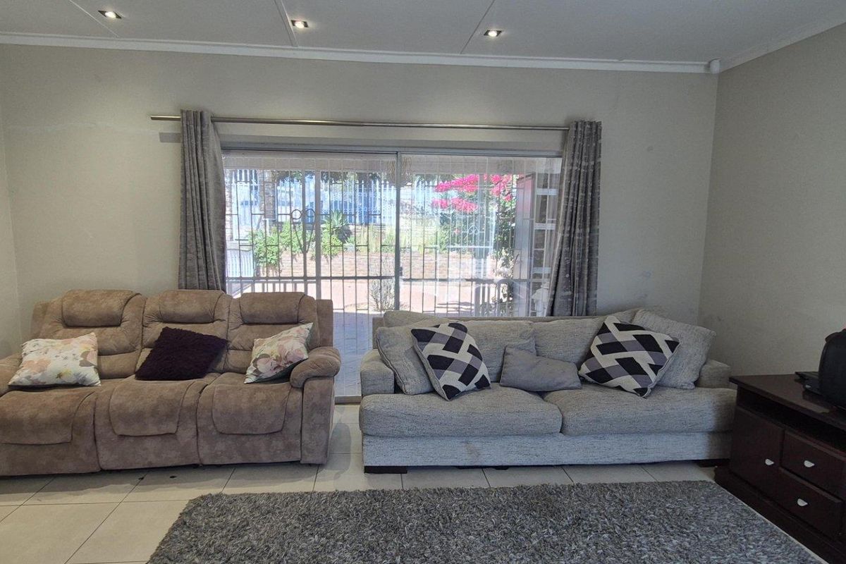 A comfortable living room featuring tiled flooring, recessed downlighting, and a large sliding glass door providing access to the outdoor area.