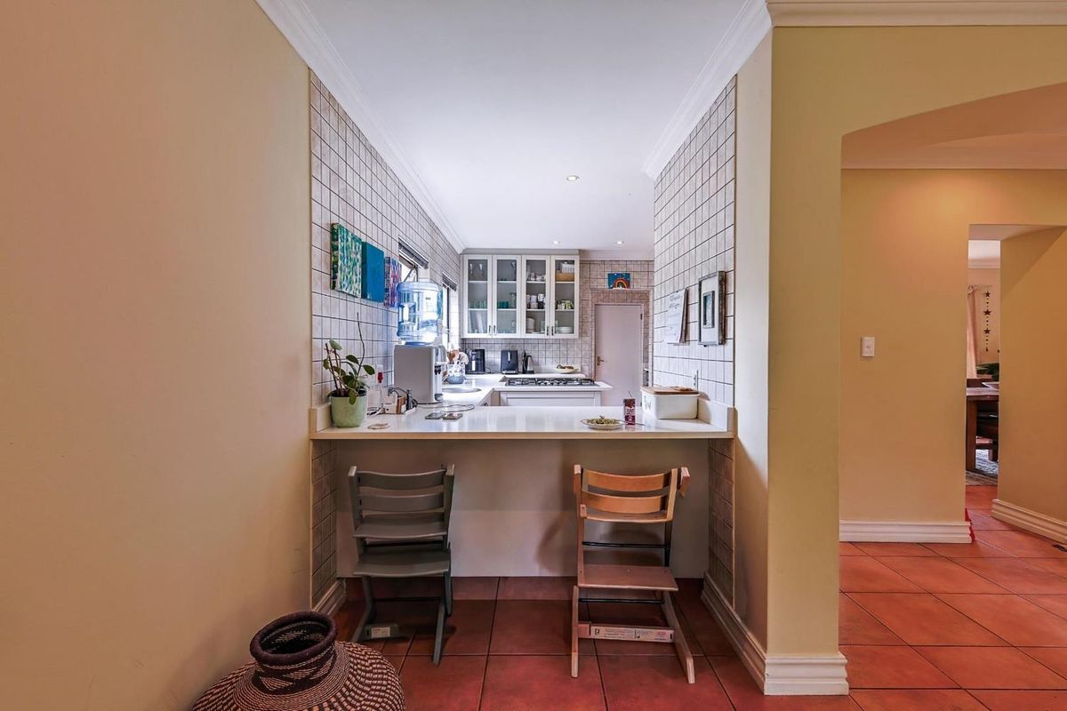 A functional kitchen featuring a breakfast bar, tiled splashbacks, and built-in cabinetry, providing a practical workspace for daily meal preparation.