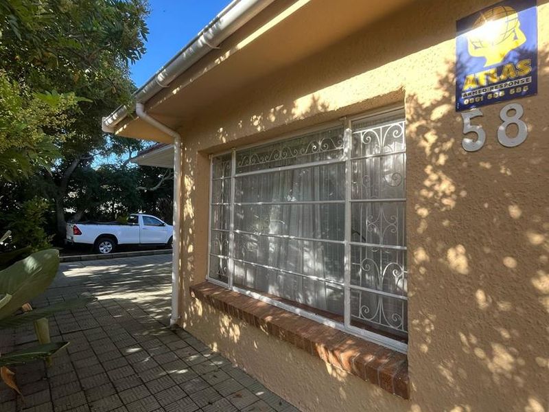 Front exterior view of the apartment featuring a paved walkway, security gate, and brick window sill detail.
