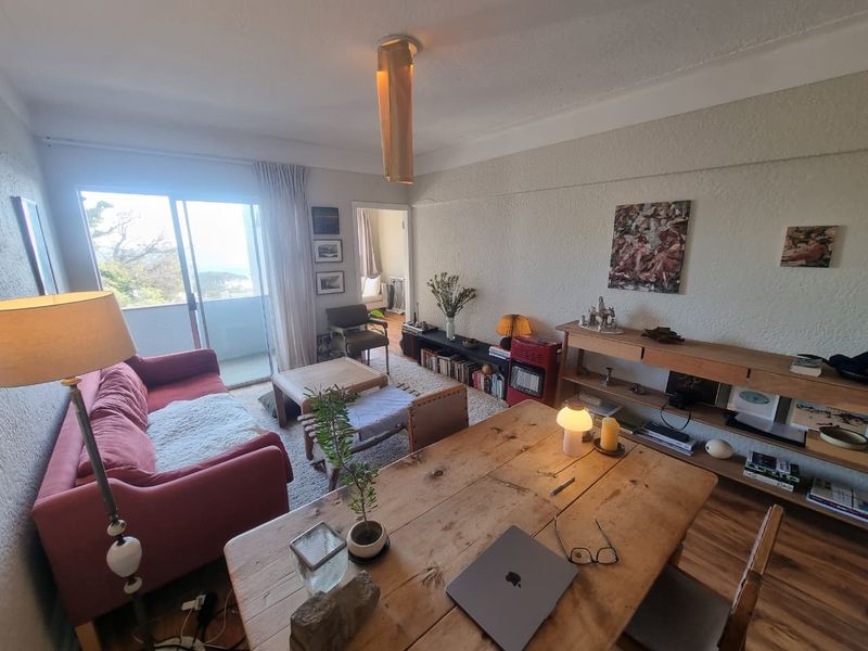 Open plan living and dining area featuring textured walls, hardwood flooring, and a sliding glass door leading to a balcony.