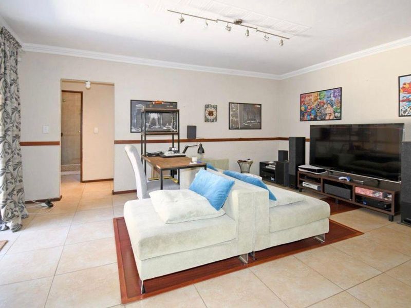A spacious living room featuring tiled flooring, chair rail molding, and direct access to an outdoor area through a sliding glass door.