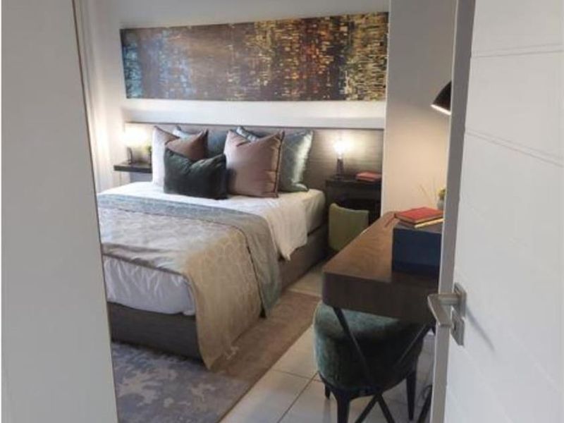 A well-maintained bedroom featuring tiled flooring, neutral wall tones, and a built-in headboard design, viewed through a doorway.