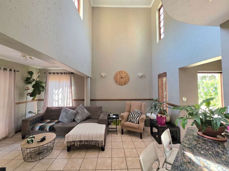 Spacious open-plan living area featuring double-volume ceilings, ceramic tiled flooring, and a granite-topped kitchen counter, offering a bright and airy atmosphere.