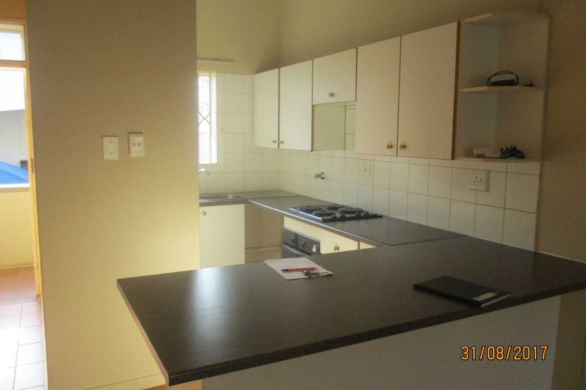 A functional kitchen featuring built-in cabinetry, laminate countertops, an electric hob, and a breakfast bar, offering a practical layout for daily use.
