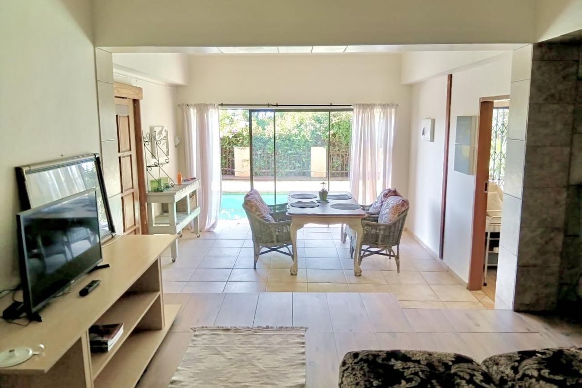 Open plan living and dining area featuring tiled flooring and large sliding glass doors providing direct access to the outdoor pool area.
