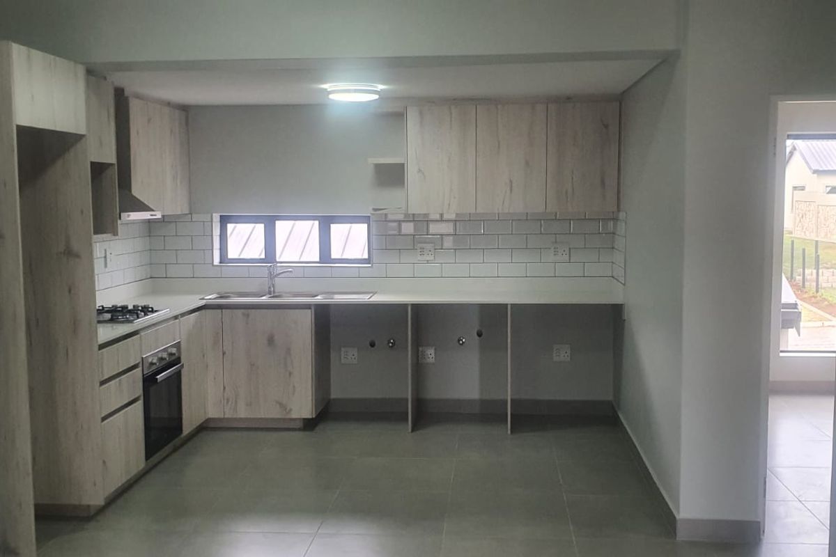Modern kitchen featuring light wood-grain cabinetry, subway tile backsplash, built-in gas hob, electric oven, and tiled flooring in an open-plan layout.