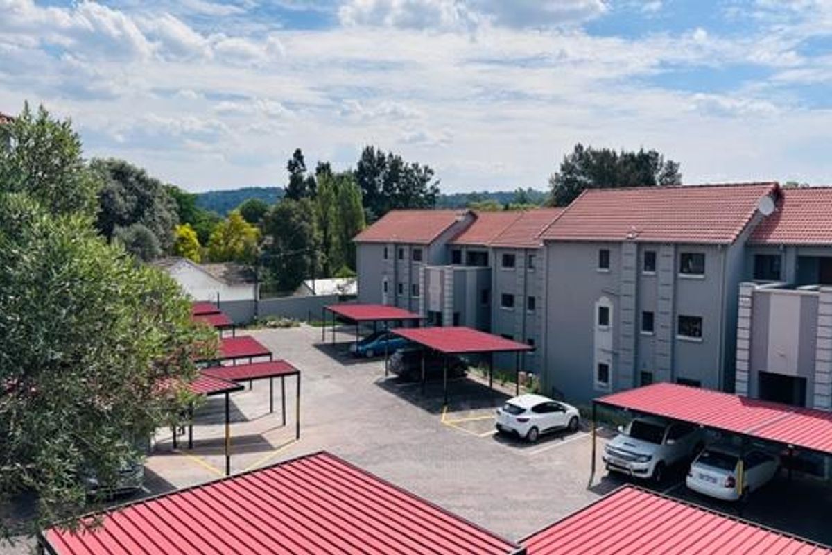 An elevated view of an apartment complex featuring multiple covered parking bays and well-maintained building exteriors with tiled roofs.