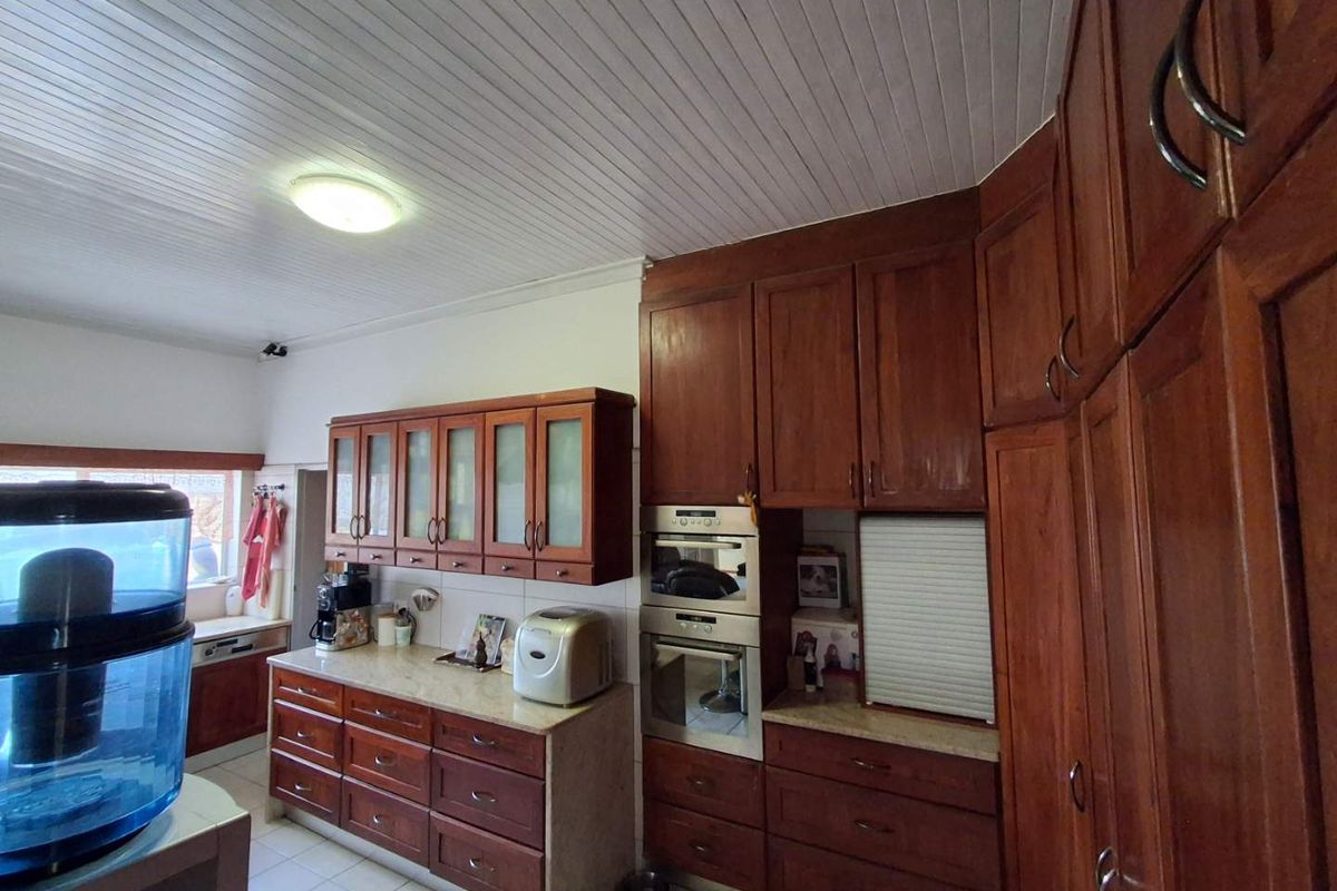 A functional kitchen featuring traditional timber cabinetry, built-in wall ovens, and tiled flooring, offering ample storage and preparation space.