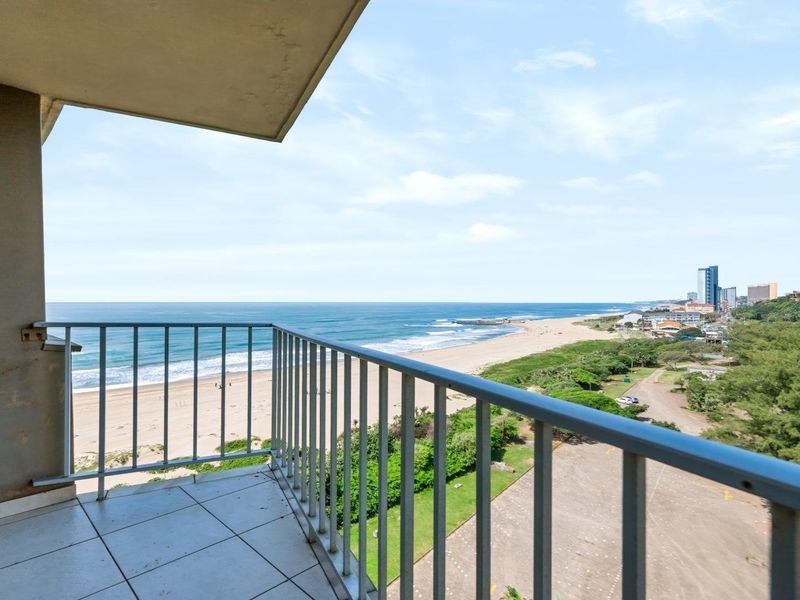 A balcony featuring tiled flooring and a metal balustrade, offering expansive views of the coastline and beach.