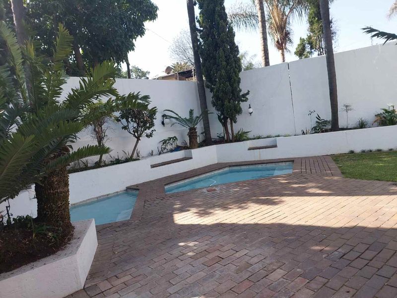 Outdoor pool area featuring a swimming pool, brick paved patio, and built-in retaining walls with integrated seating.