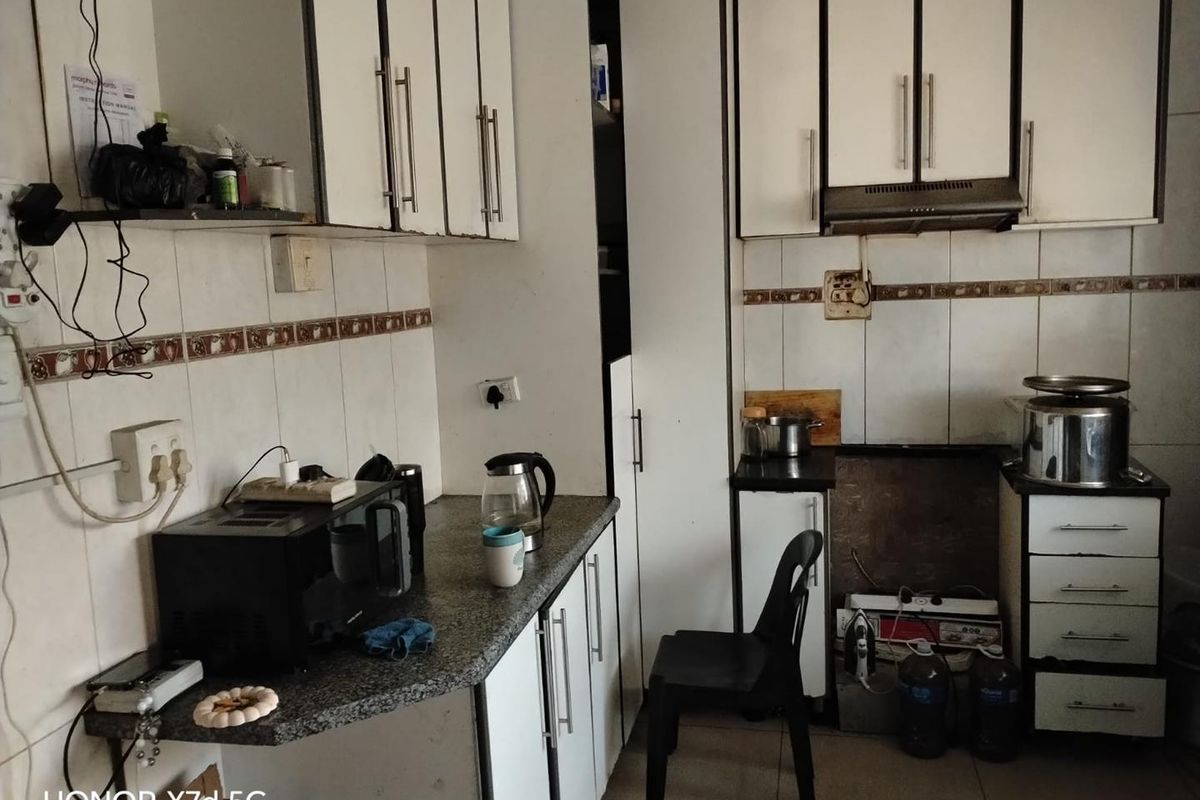 A functional kitchen space featuring white cabinetry, granite-look countertops, and tiled splashbacks, currently requiring updates to the built-in appliance housing.