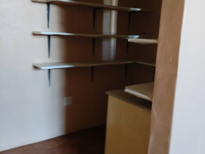 A functional scullery or pantry area featuring built-in shelving and cabinetry, providing ample storage space for household organization.