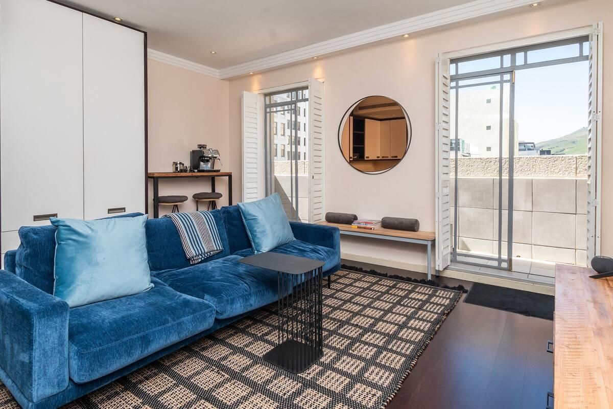 A well-maintained living room featuring built-in cupboards, recessed lighting, and direct access to a private balcony through shutter doors.