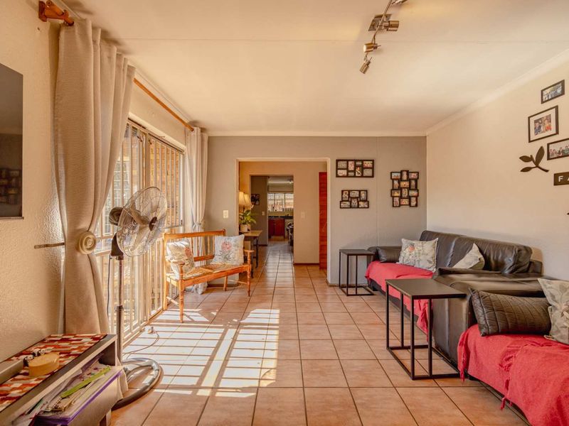 Spacious living area featuring tiled flooring, track lighting, and a large sliding glass door providing natural light and access to the exterior.