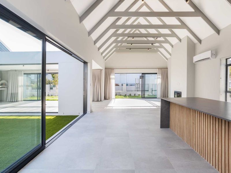 Spacious open-plan living area featuring a vaulted ceiling with exposed rafters, large sliding glass doors, and a modern kitchen island.