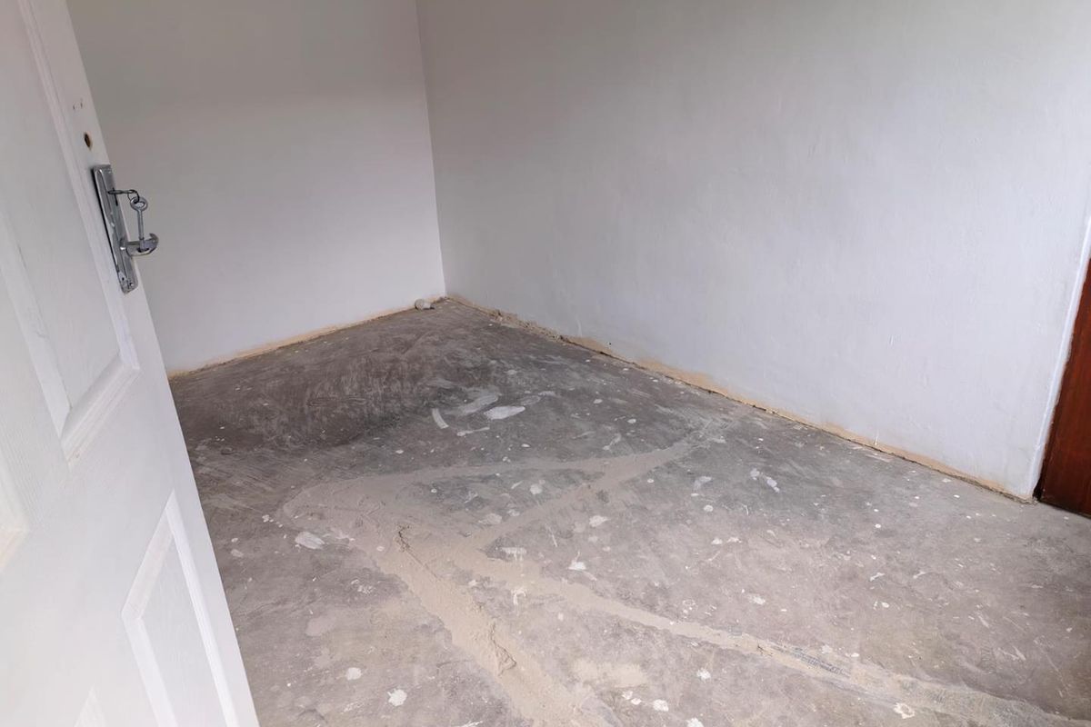 An empty bedroom featuring unfinished concrete flooring and plain white walls, ready for new floor finishes and interior design.