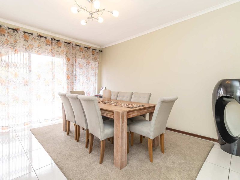 A bright dining room featuring tiled flooring and a large sliding glass door that provides ample natural light.