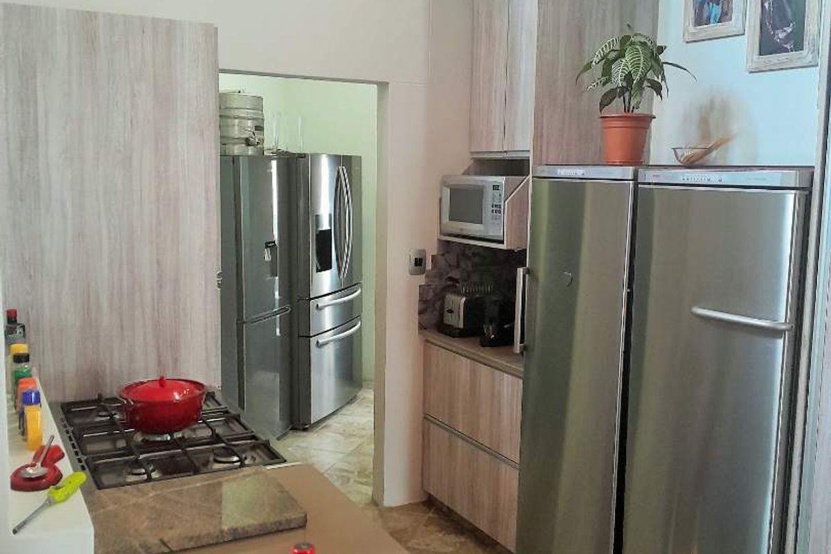 Modern kitchen featuring light wood-grain cabinetry, stone countertops, a built-in gas hob, and a convenient adjacent scullery area with additional refrigeration.