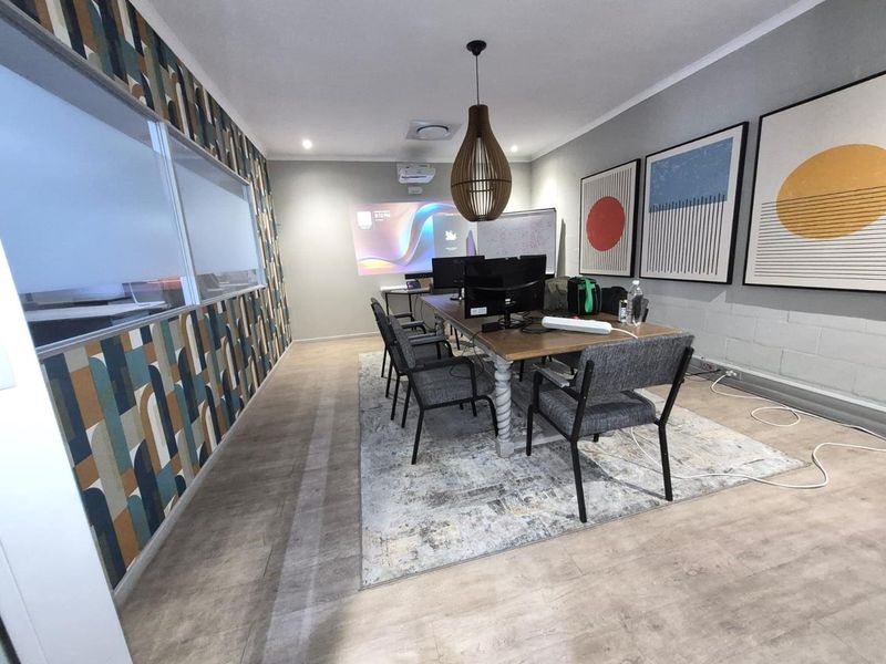 A modern office meeting room featuring a projector, glass partition wall, and contemporary patterned wallpaper, providing a professional and functional workspace.