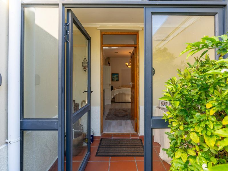 A covered entrance area featuring terracotta floor tiles and an aluminium framed glass door leading into the home interior.