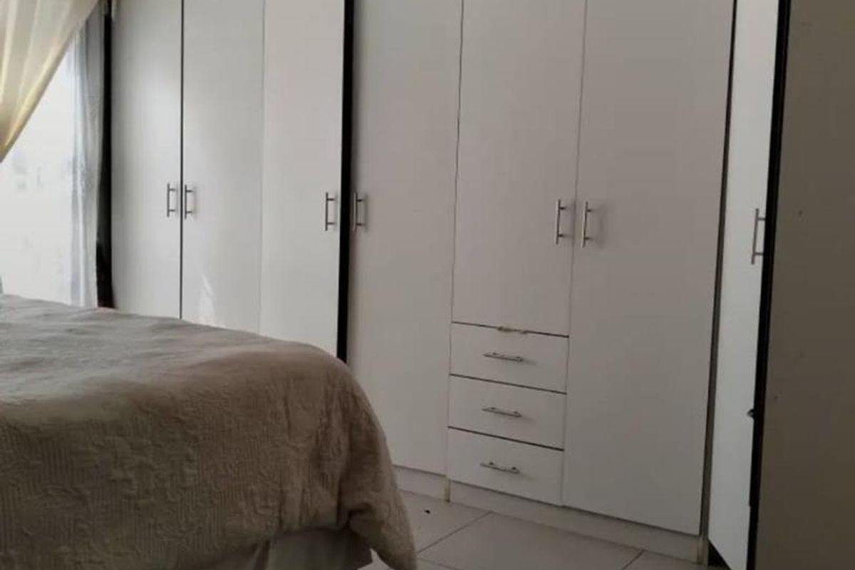 A bedroom featuring built-in white cabinetry with integrated drawers and tiled flooring.