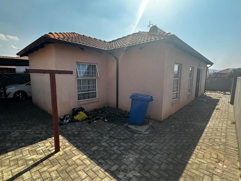 Rear exterior view of the house featuring a paved courtyard, tiled roof, and solar water heating system.