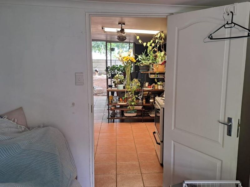 A view through a doorway into an adjacent living area with tiled flooring and a sliding glass door leading to the exterior.