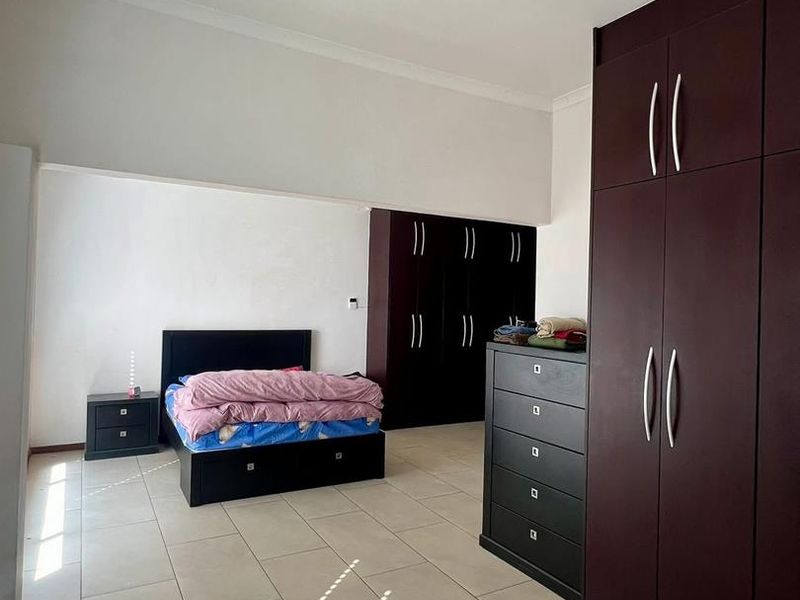 Spacious bedroom featuring large dark wood built-in cupboards and neutral tiled flooring throughout.