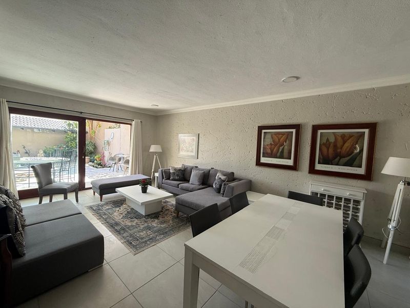 Spacious open-plan living and dining area featuring tiled floors, textured walls, and large sliding glass doors providing direct access to the outdoor patio.