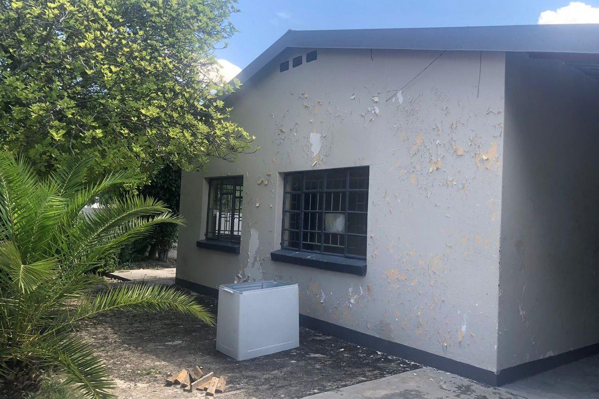 Exterior view of the property showing significant paint deterioration on the facade and metal security bars on the windows.