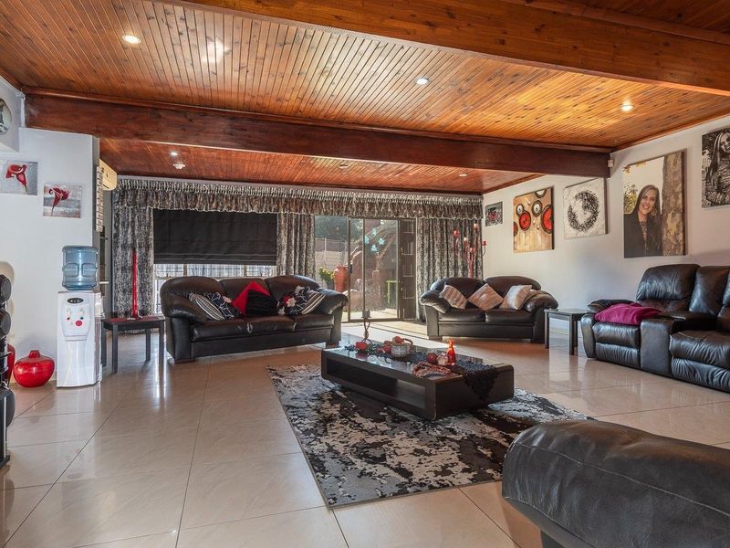 Spacious living room featuring a warm timber-clad ceiling with exposed beams, tiled flooring, and large sliding glass doors providing access to the outdoor area.